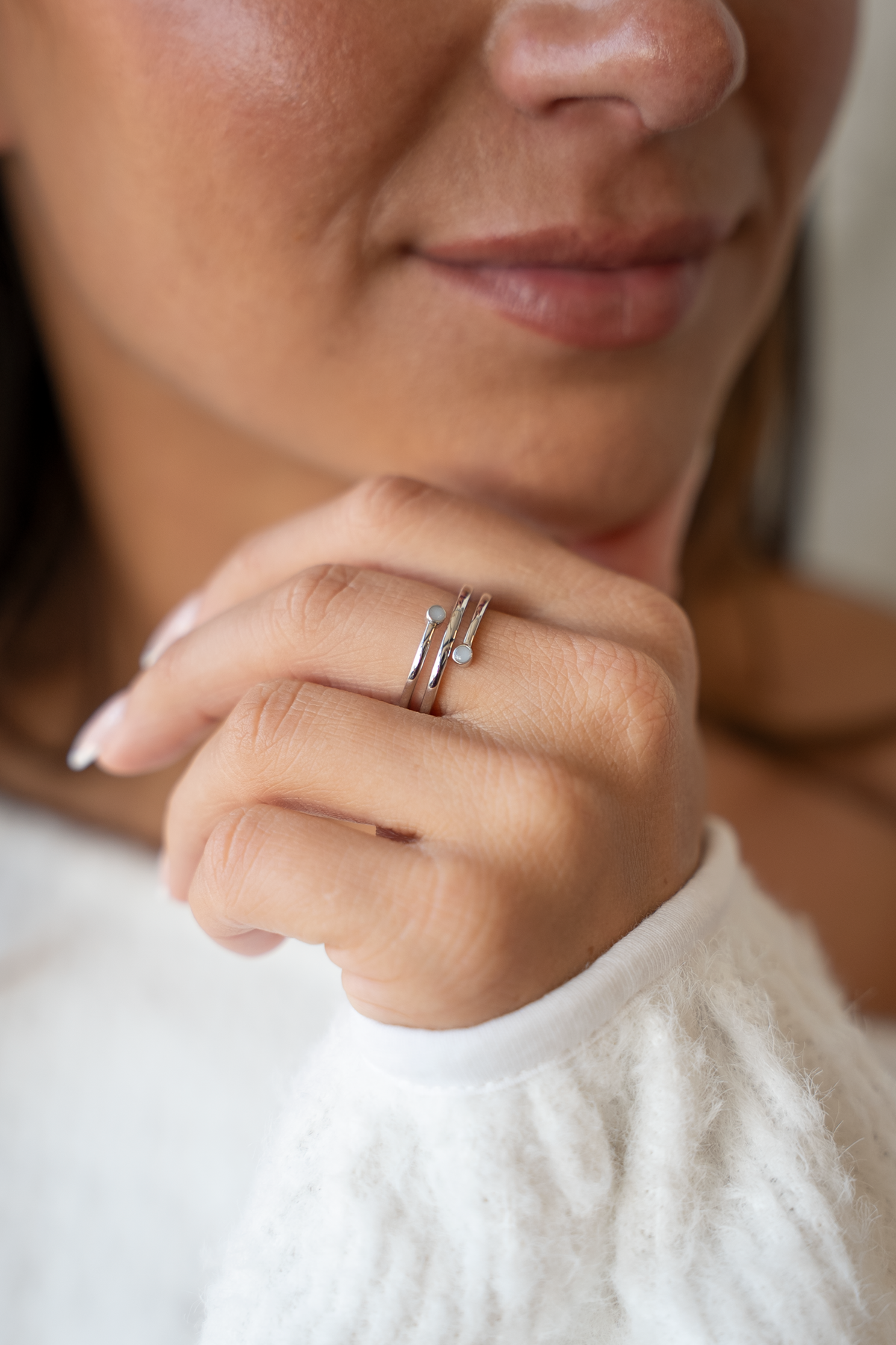 Woman resting her chin on her hand wearing the silver Aurore spiral breast milk ring