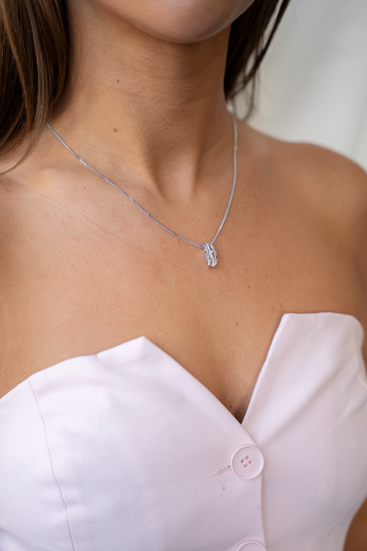 Side view of the silver Charlotte breast milk pendant on a fine chain with a pale pink top