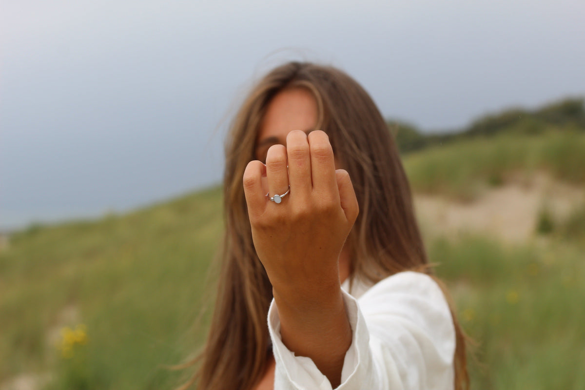 Woman in the dunes holding out her hand, wearing the silver Elisa breast milk ring