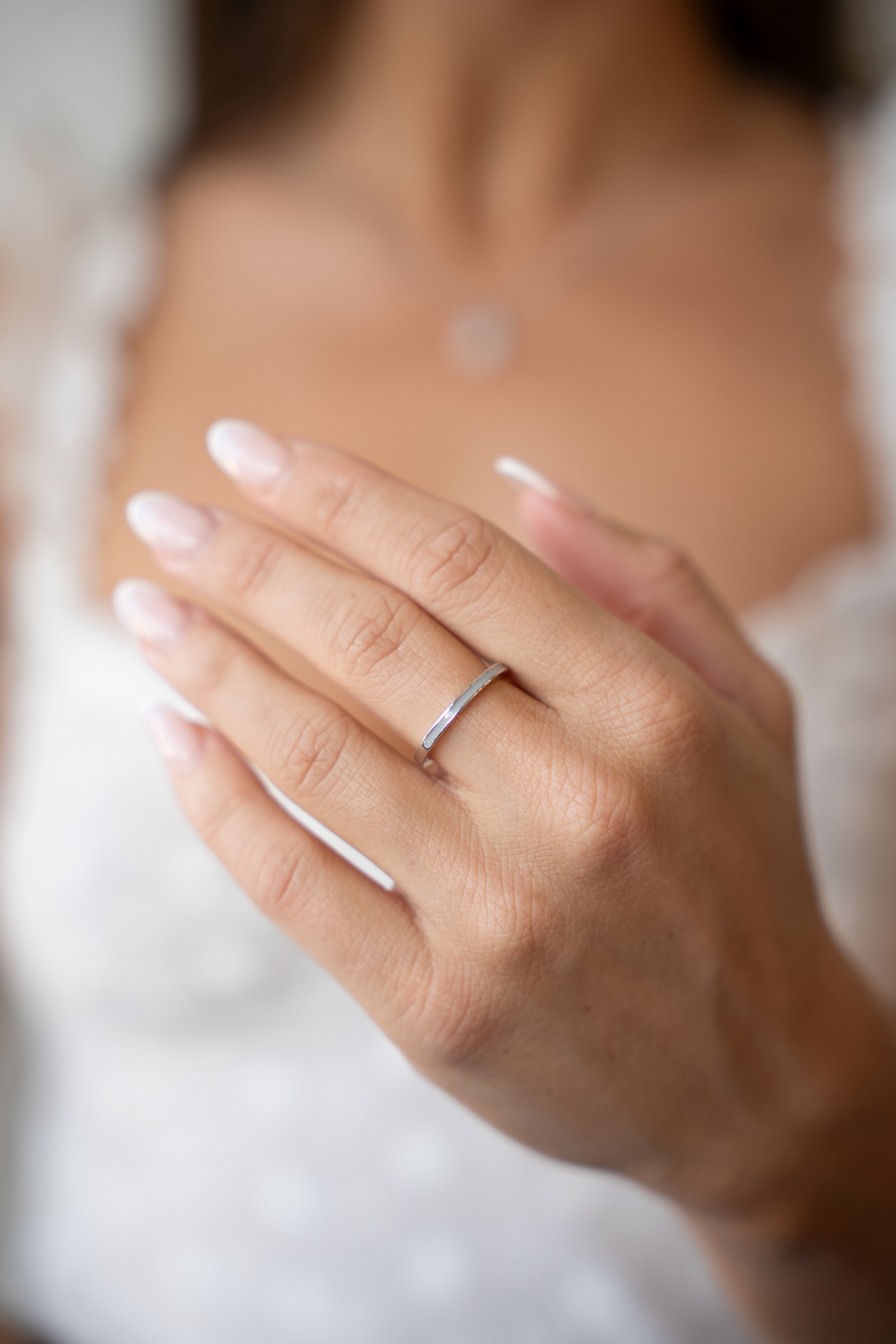 Close-up of a hand wearing the slim silver Eva ring with a white milk inlay