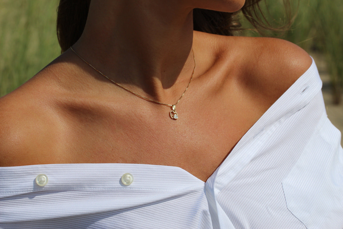 Close-up of a woman wearing the Heart to Heart breast milk pendant in yellow gold on a gold chain