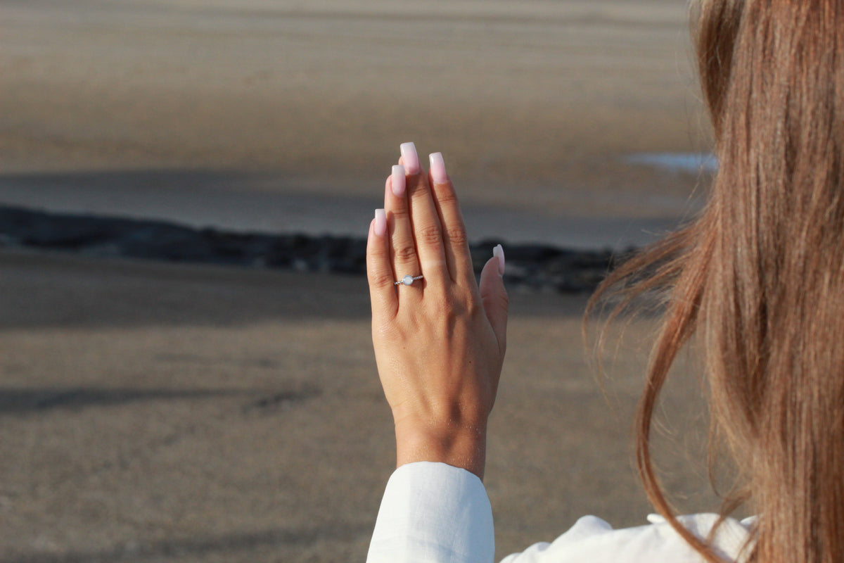 Back of a raised hand at the beach, wearing the beaded silver Isabelle breast milk ring