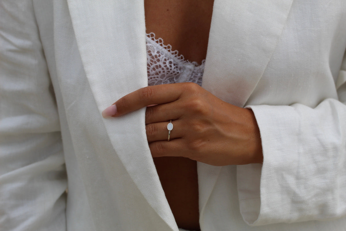 Hand at the opening of a white blazer over lace, wearing the silver Juna breast milk ring