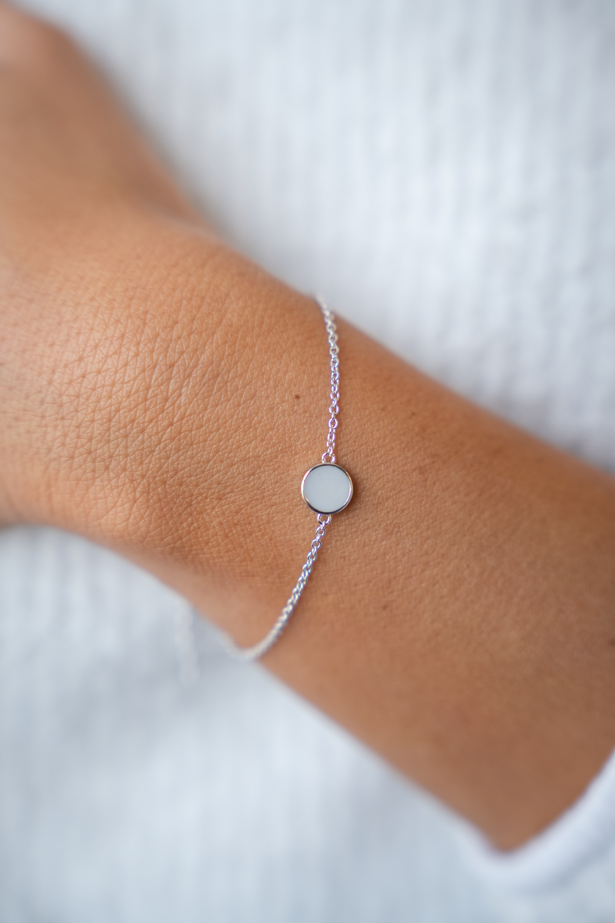 Close-up of the silver Lis breast milk bracelet with flat round milk stone on a wrist