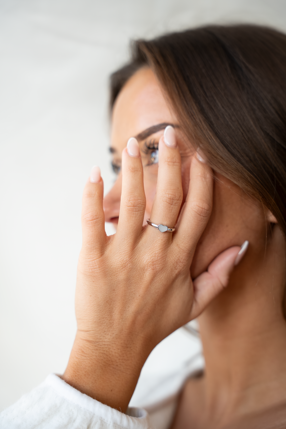 Lisa heart ring in white gold on the finger, hand held in front of the face