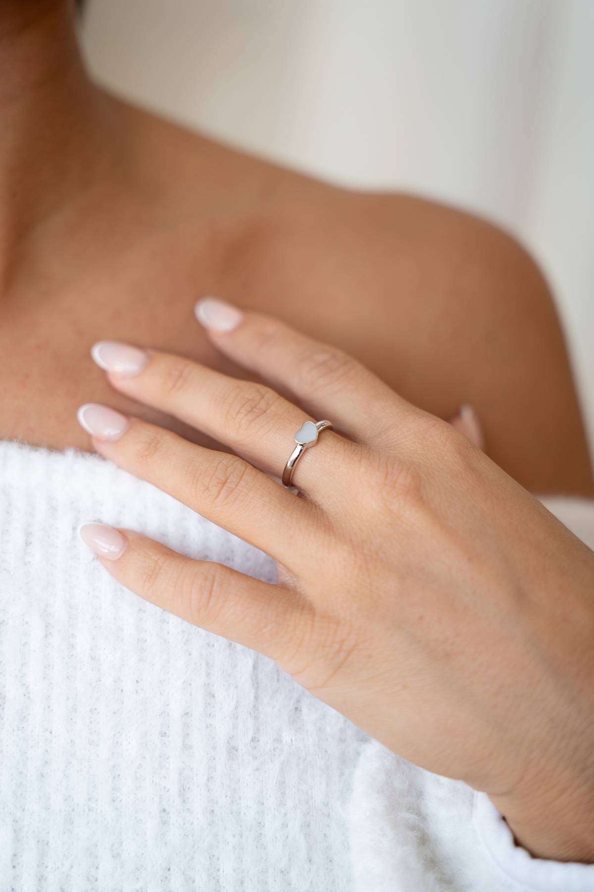 Lisa heart ring in white gold on the finger, hand on the shoulder above a white knit top