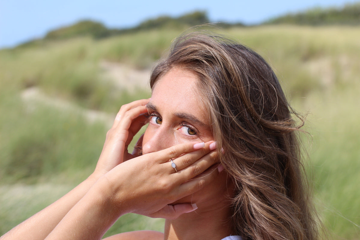 Silver Luna breast milk ring worn on the finger, hands held in front of the face