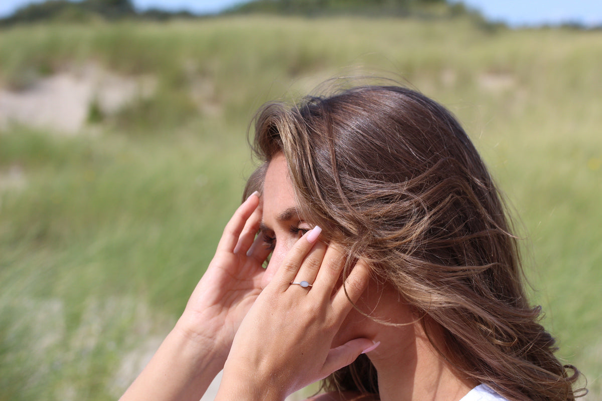 Silver Luna breast milk ring worn on the finger, hands in the hair in the dunes