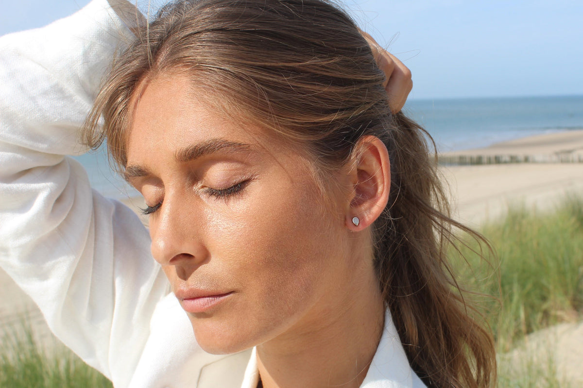 Woman with closed eyes and hand in her hair, small teardrop Mini Drop stud in her ear