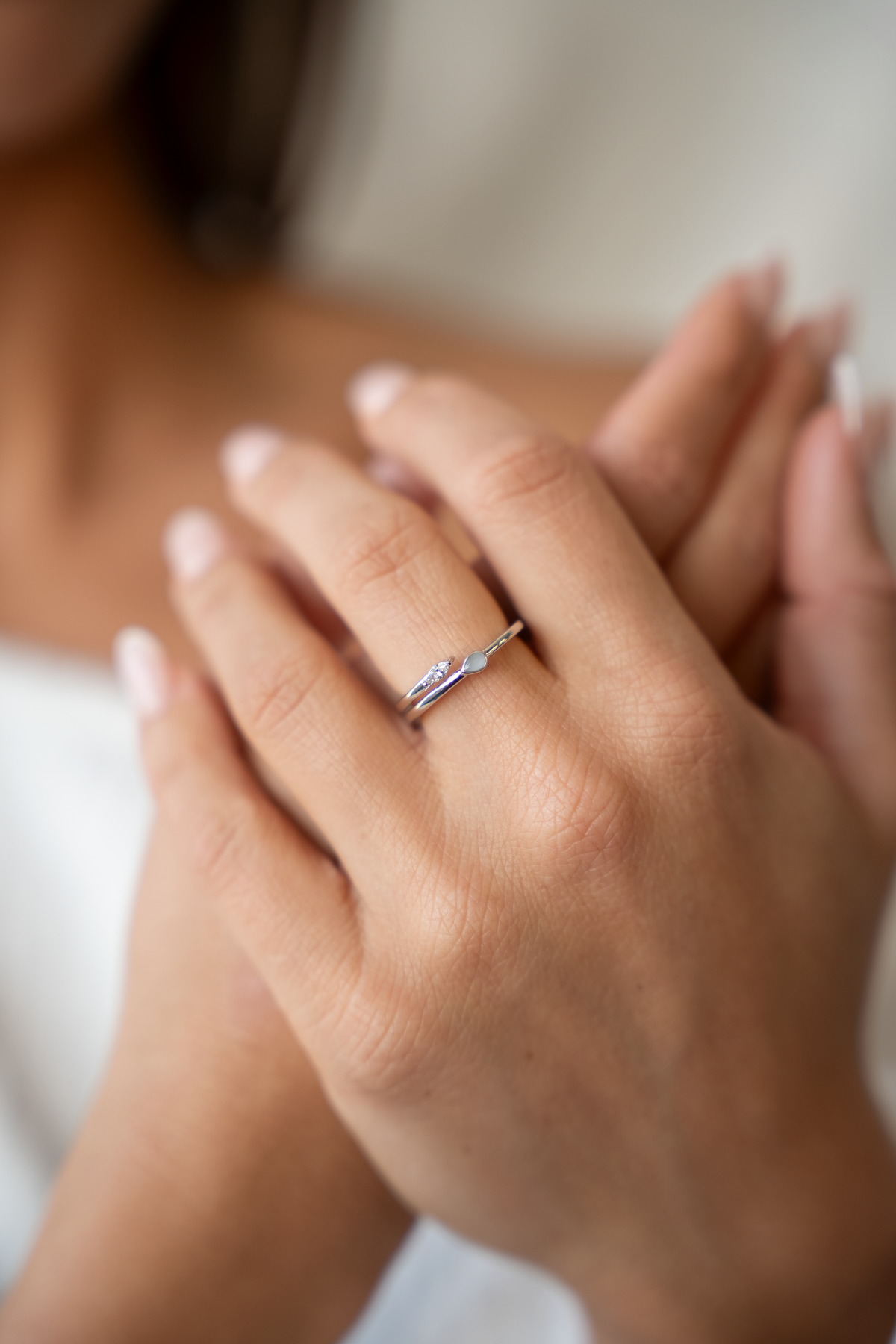Naomi open breast milk ring in white gold on the finger, hands crossed, close-up of the open ring