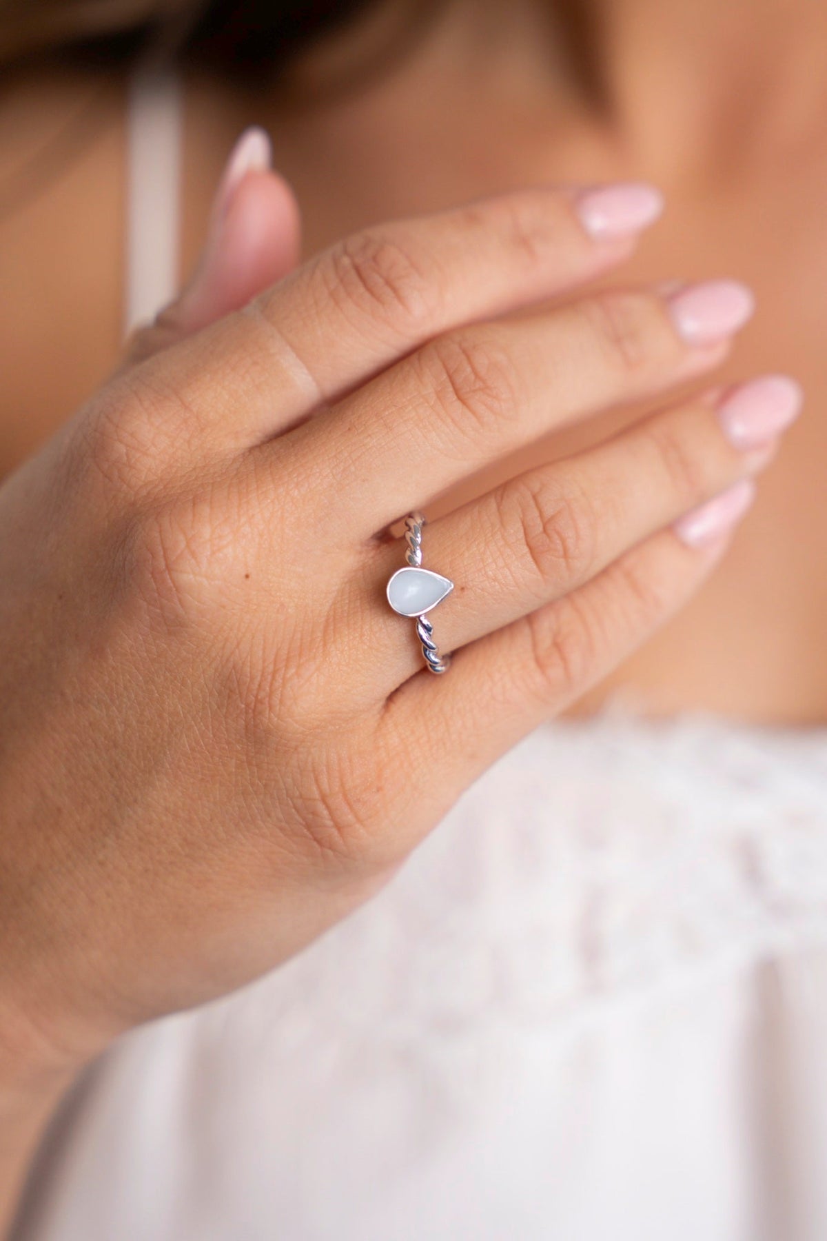 Close-up of the silver Turning Droplet ring with a twisted band and breast milk drop.