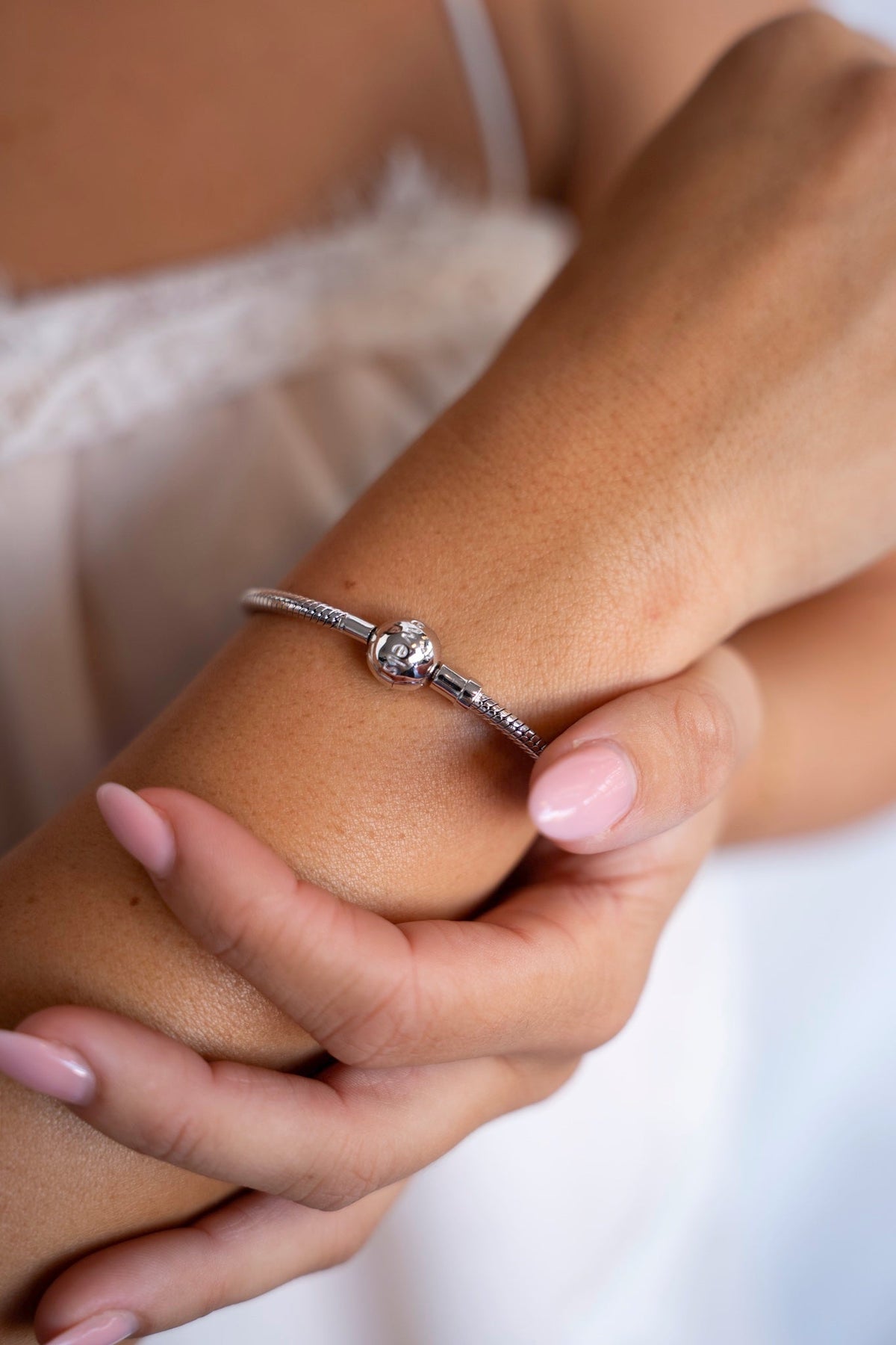 Silver charm bracelet with a round clasp on the wrist, made for breast milk charms.